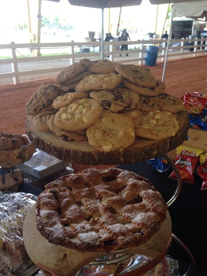 Cookies and pie displayed on wooden stands at an outdoor event.