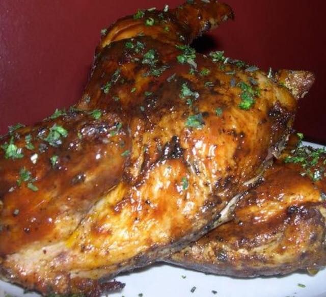 Roasted chicken with a dark, glossy glaze, sprinkled with green herbs.