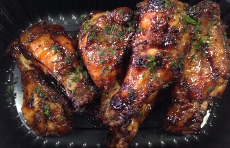 Grilled chicken drumsticks, glazed with sauce, sprinkled with herbs.