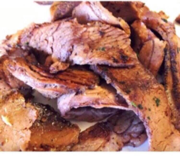 Sliced, cooked meat on a white plate; brown with grill marks.