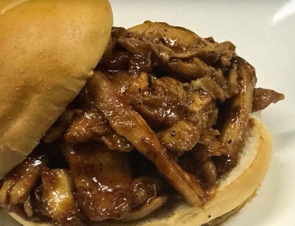 Pulled mushroom sandwich on a bun with dark, glossy sauce.