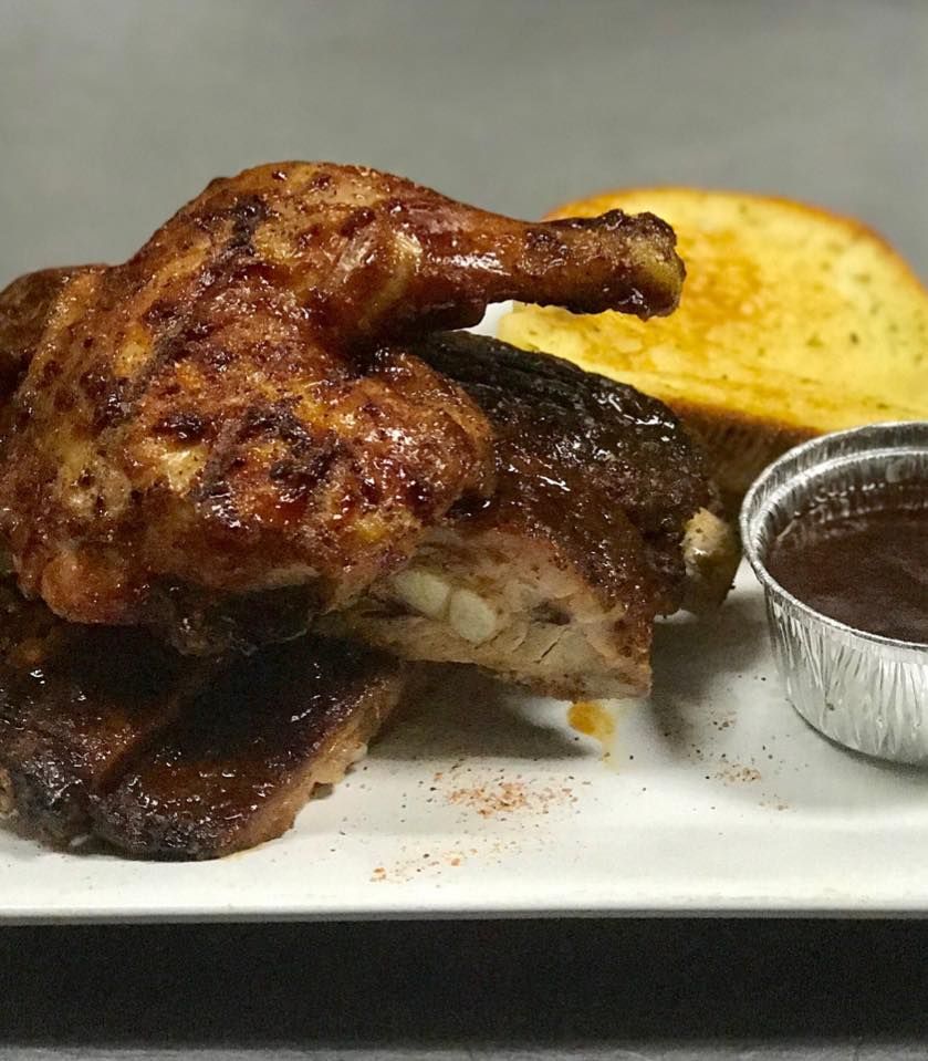 Grilled chicken, ribs, and garlic toast with barbecue sauce on a white plate.