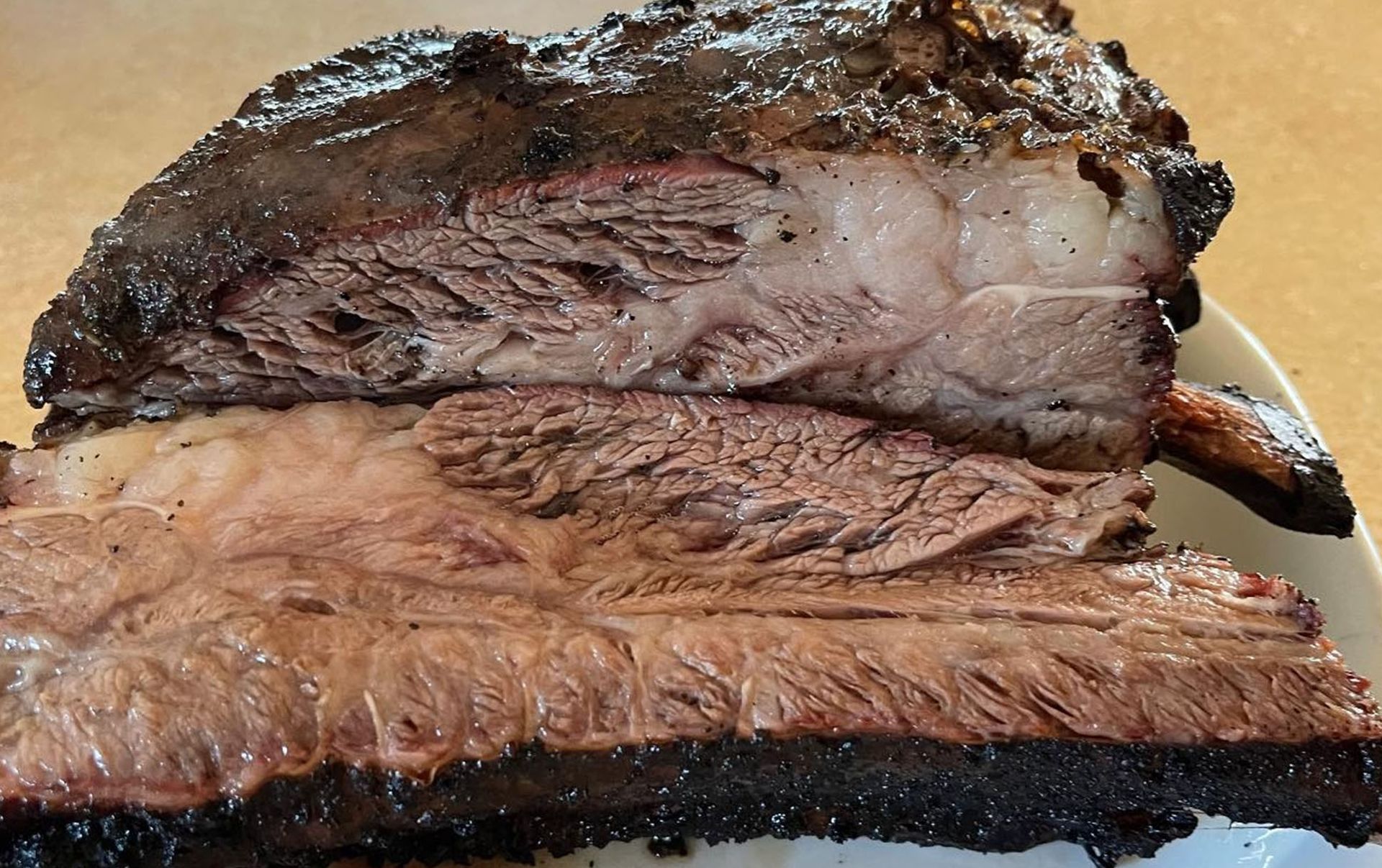 Sliced smoked beef brisket, showing moist, reddish-brown meat with a dark crust.