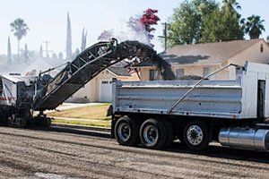 A dump truck is being pulled by a machine on a road.