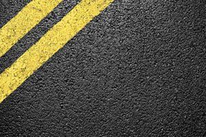 A close up of a road with two yellow lines on it.