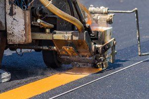 A machine is painting a yellow line on the road.