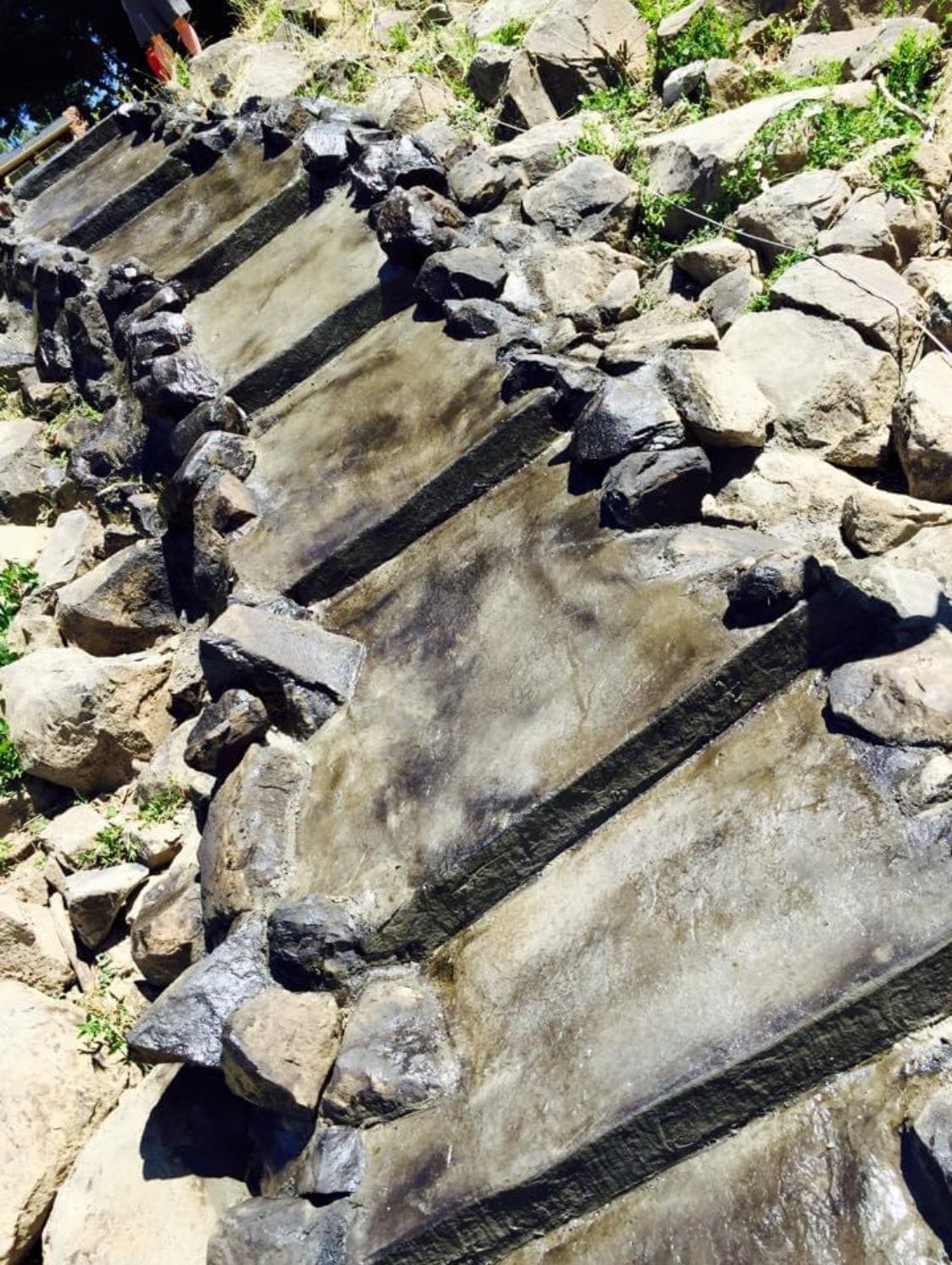 Concrete tiered water feature with rocks, likely outdoors.