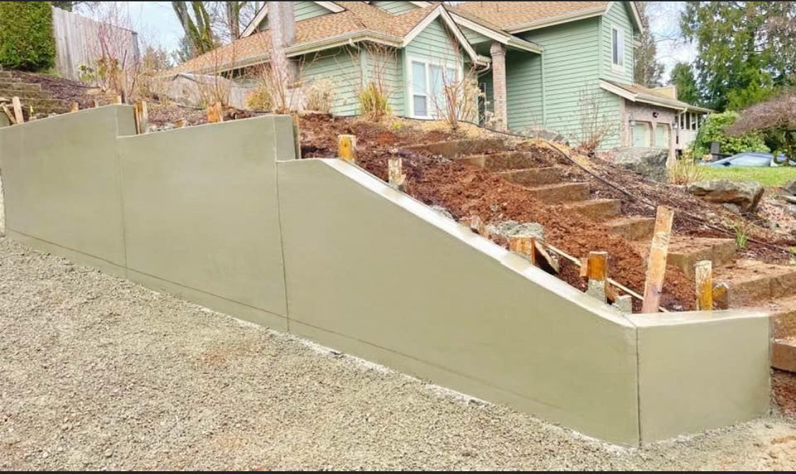 Beige retaining wall in front of a house, with steps and dirt landscaping.