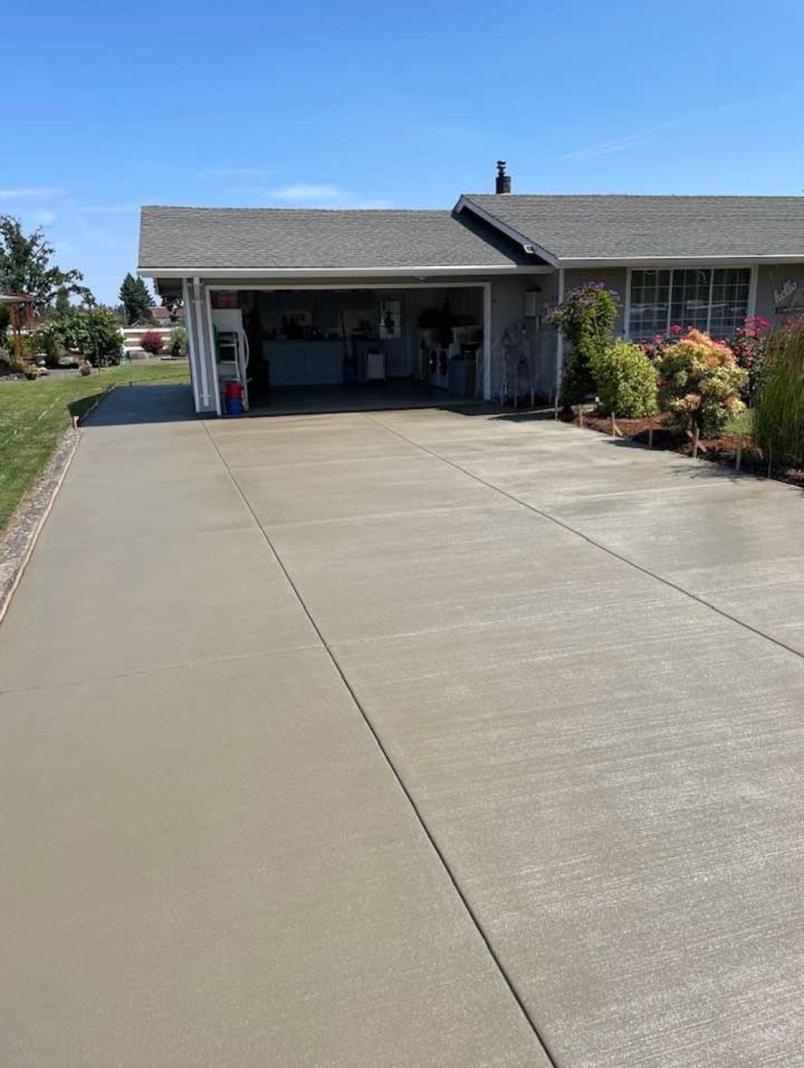 New concrete driveway leading to a garage on a sunny day.