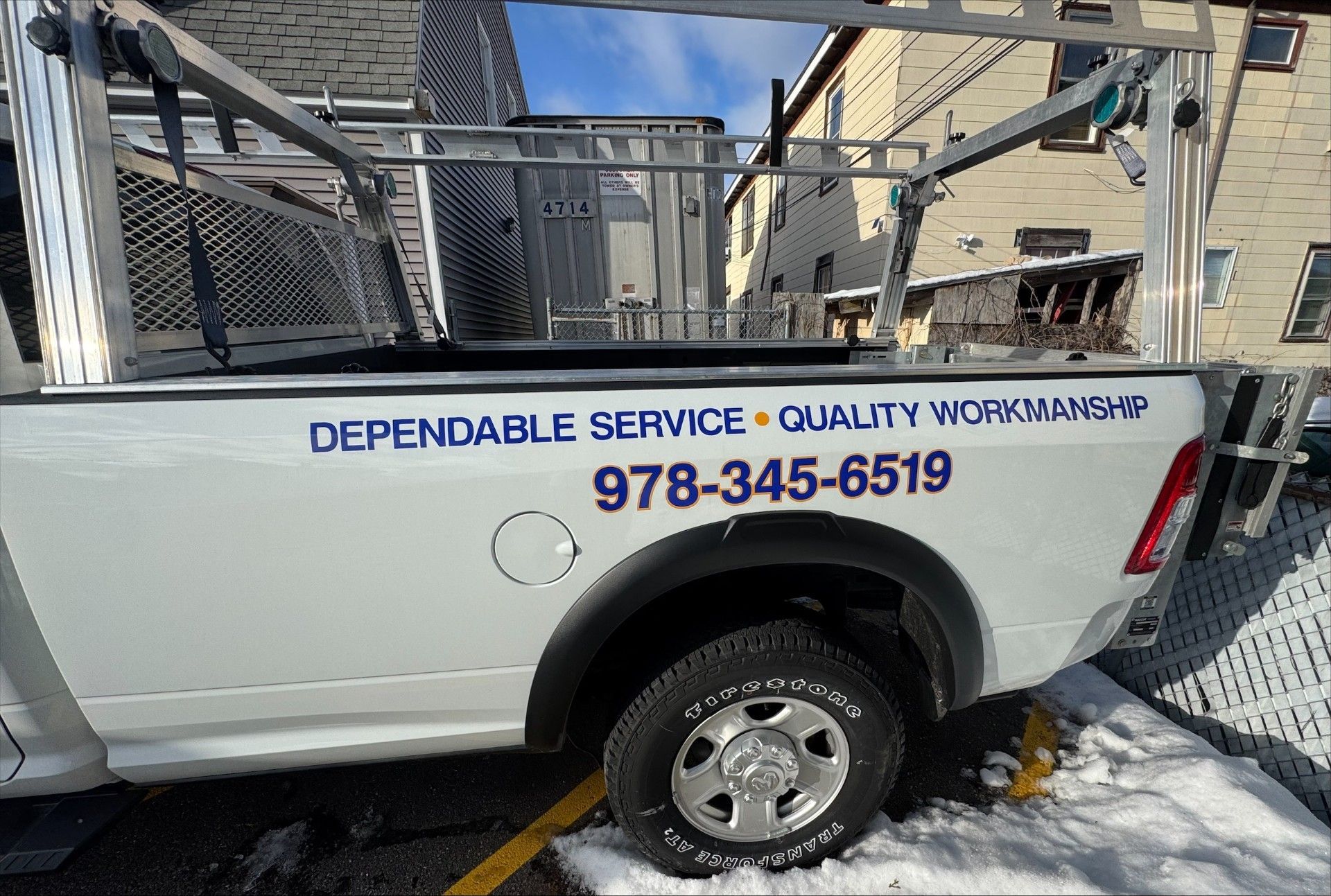 White pickup truck with ladder rack, phone number, and 