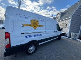White plumbing service van parked outside a building, with logo and phone number visible.