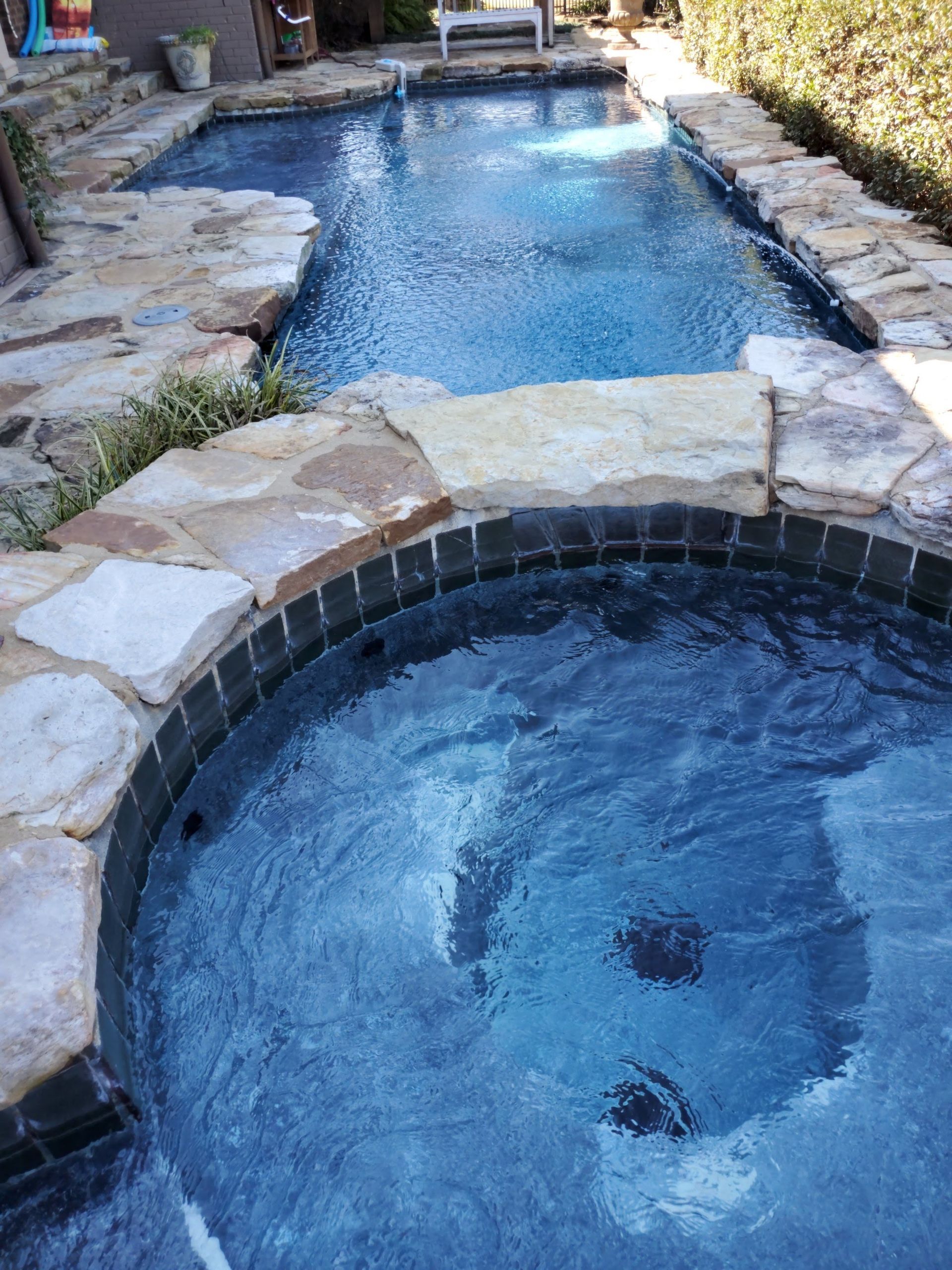 A swimming pool with a hot tub in the middle of it.