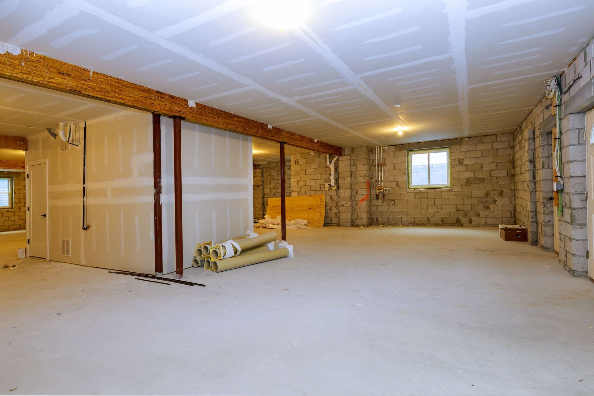 Unfinished basement with drywall, exposed brick, insulation, and a concrete floor under construction