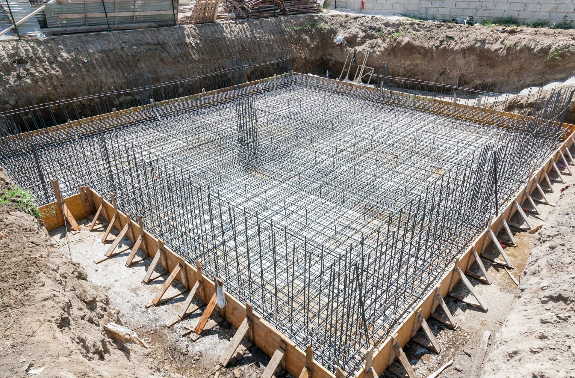 Concrete foundation rebar grid inside wooden formwork at a construction site