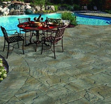 Patio with pool, wrought iron table and chairs. Stone pavers are grey-green. Wine glasses and food on the table.