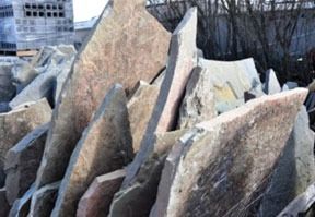 Pile of natural, irregularly shaped flagstones in various shades of brown and gray.