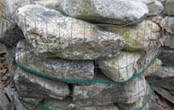 Bag of natural grey and tan river rocks, bound with green netting.