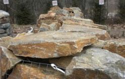 Pile of large, flat, beige and brown rocks in an outdoor setting.