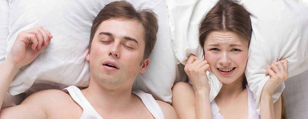 A snoring man and woman lying in bed
