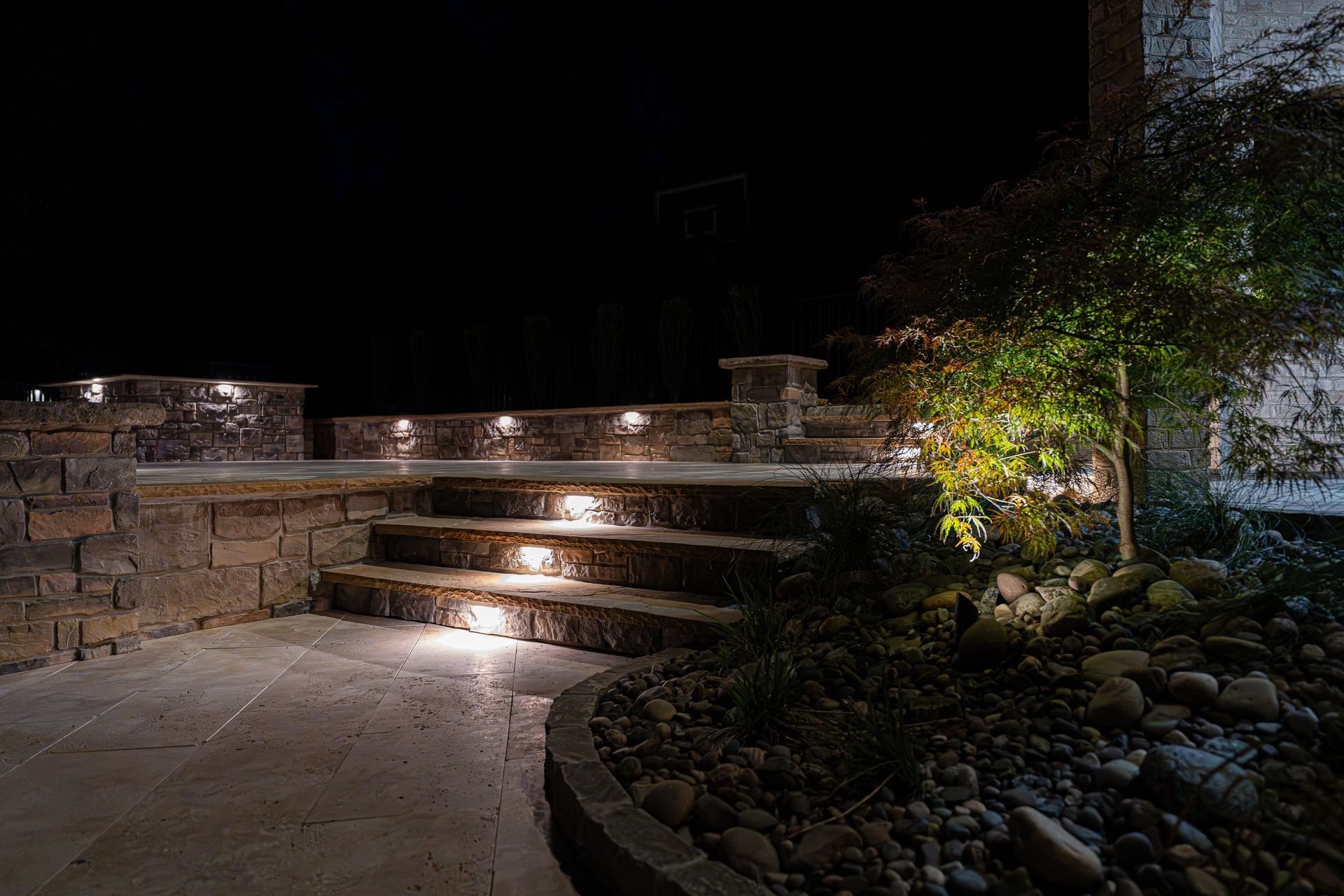 Stone steps and patio illuminated at night with built-in lighting.