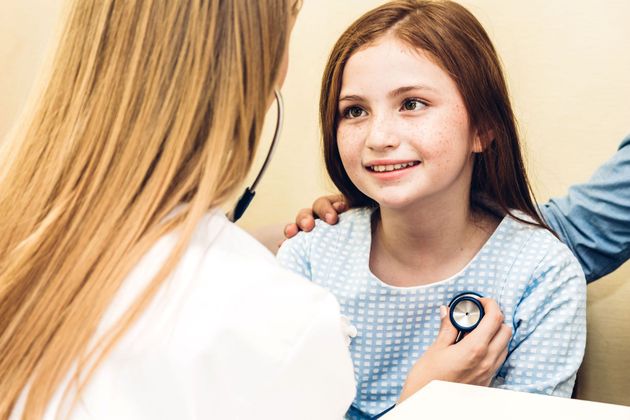 Doctor examining a smiling child with a stethoscope in a clinic