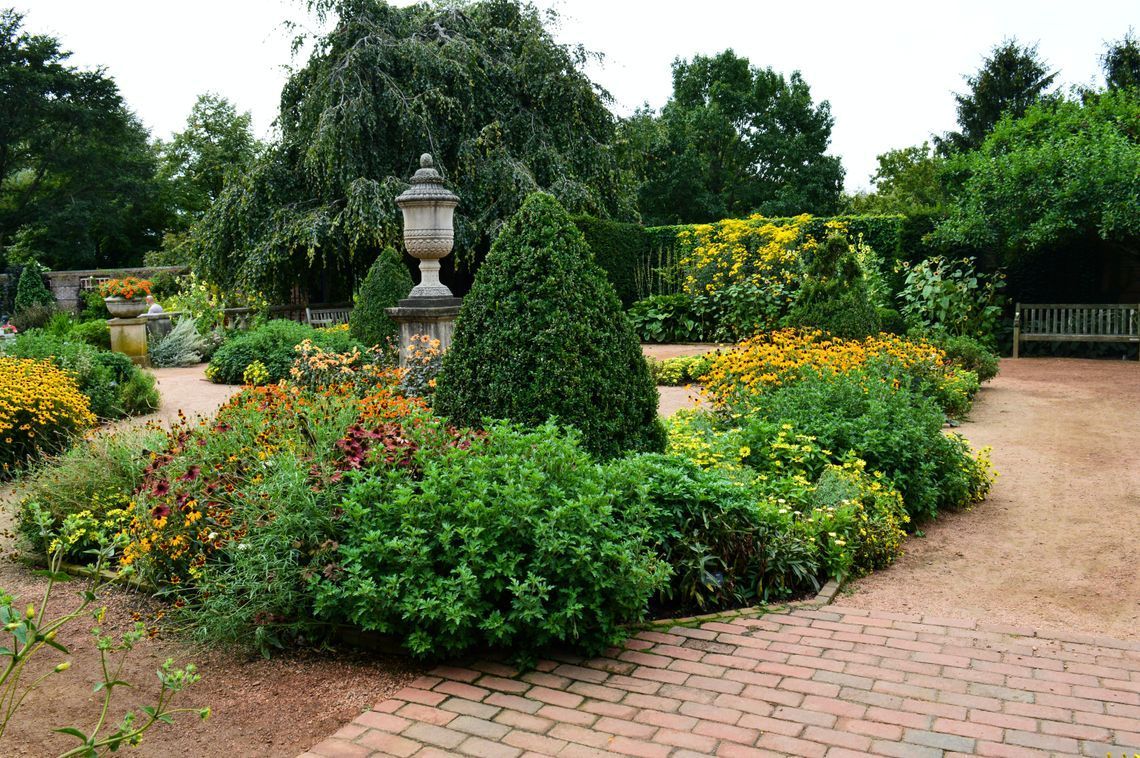 A brick walkway surrounded by flowers and bushes in a garden.