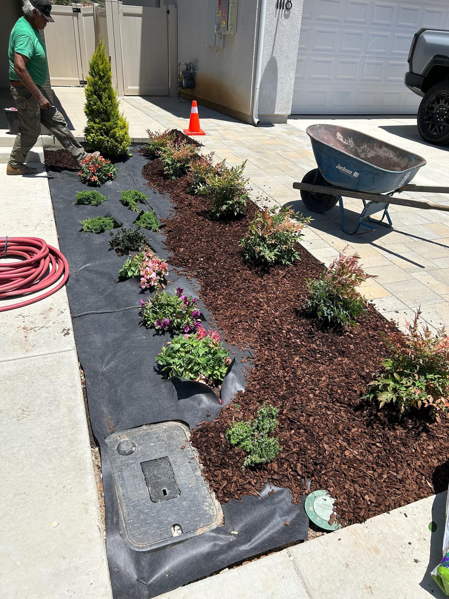 A man is planting flowers in a garden in a driveway.