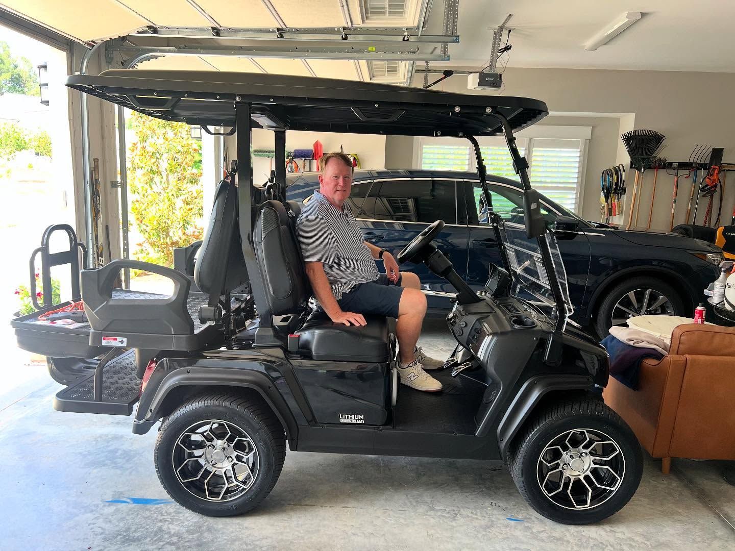 A man is sitting in a golf cart in a garage.