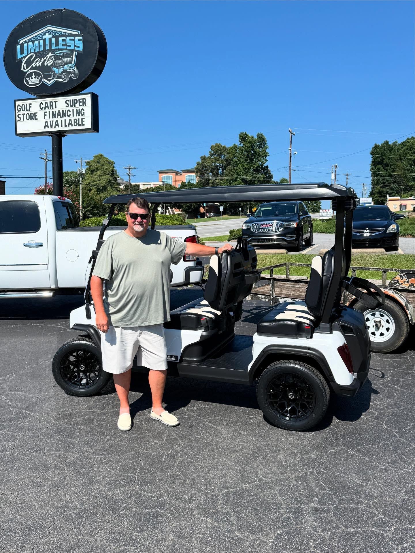 A man is standing in front of a golf cart.