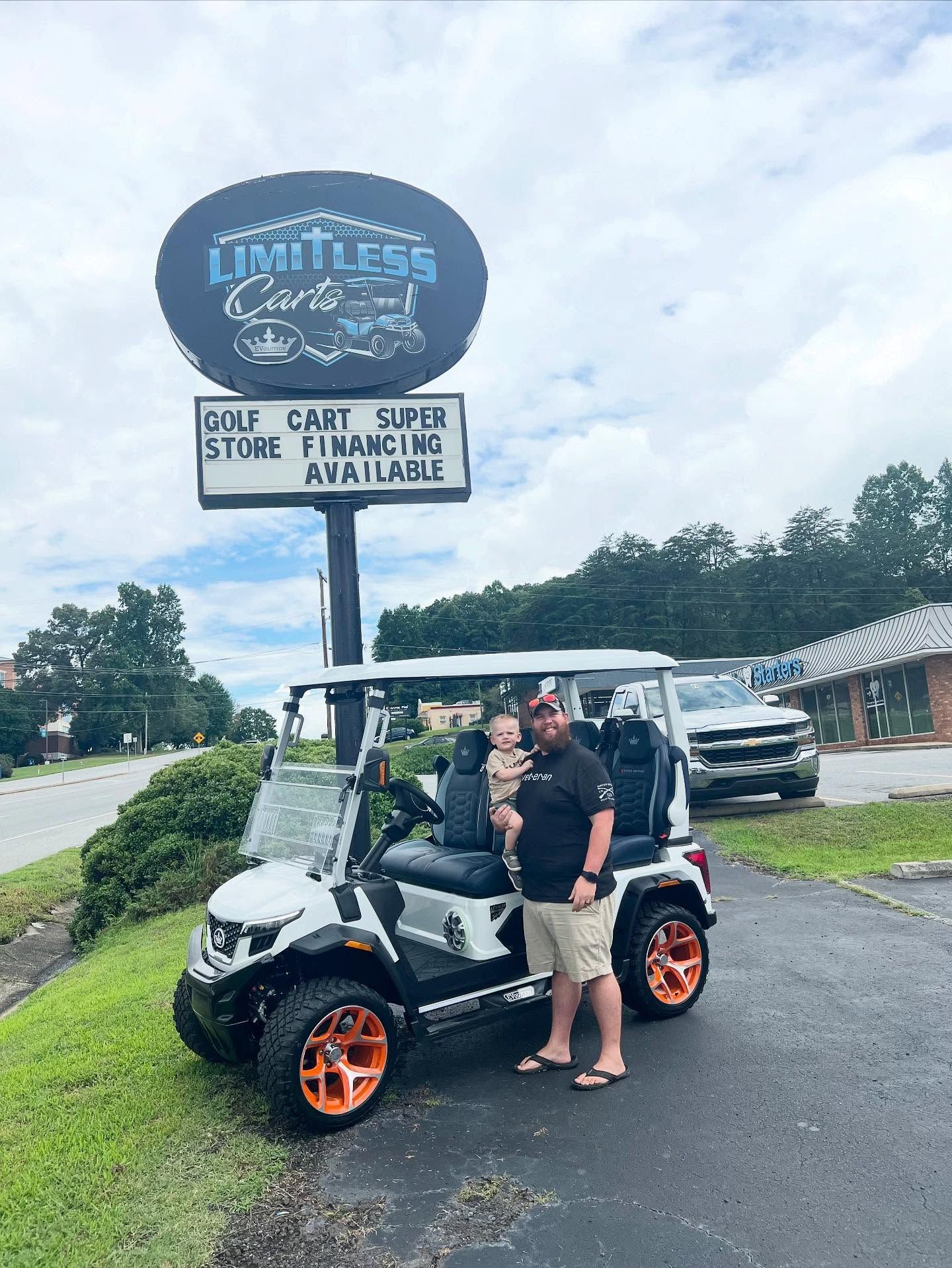 A man is holding a baby in front of a golf cart.