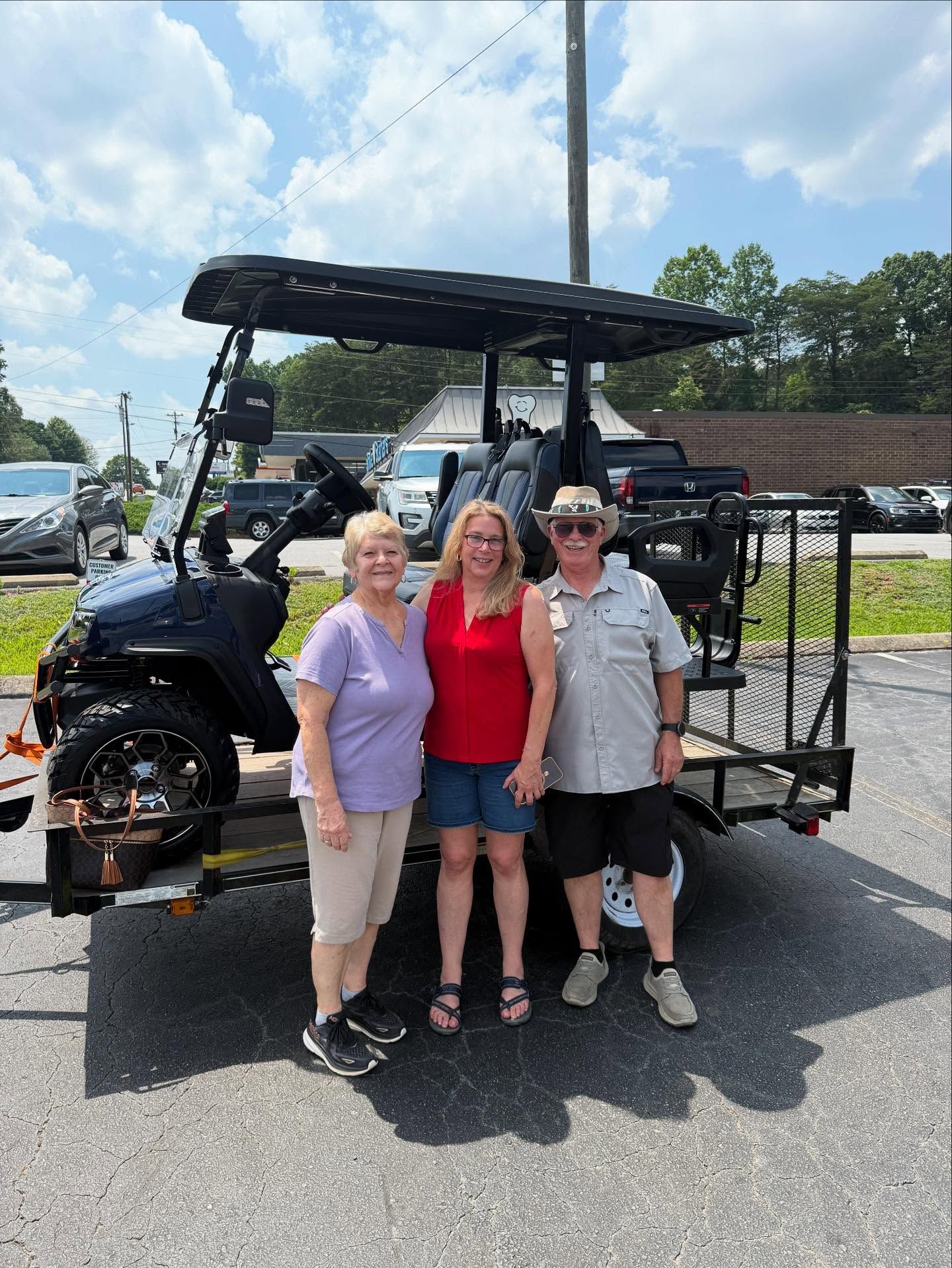 A group of people are standing in front of a golf cart.
