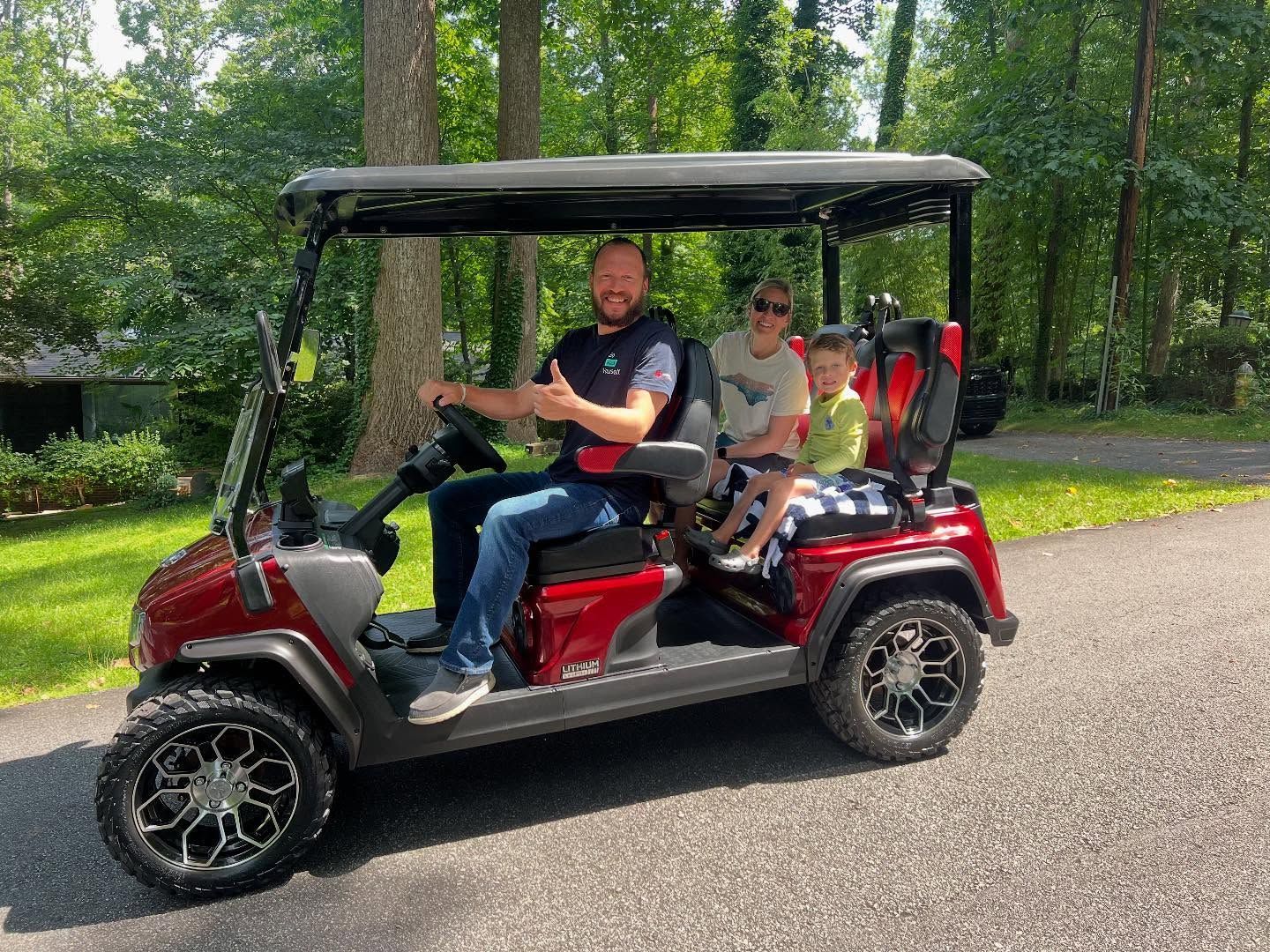 A man is driving a golf cart with two children in it.