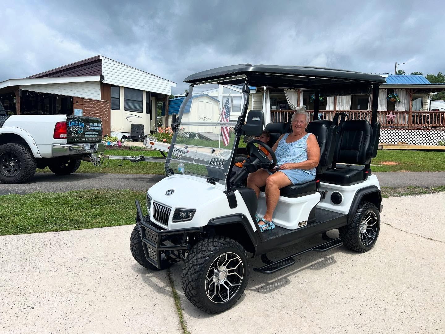 A woman is sitting in a white golf cart on the side of the road.
