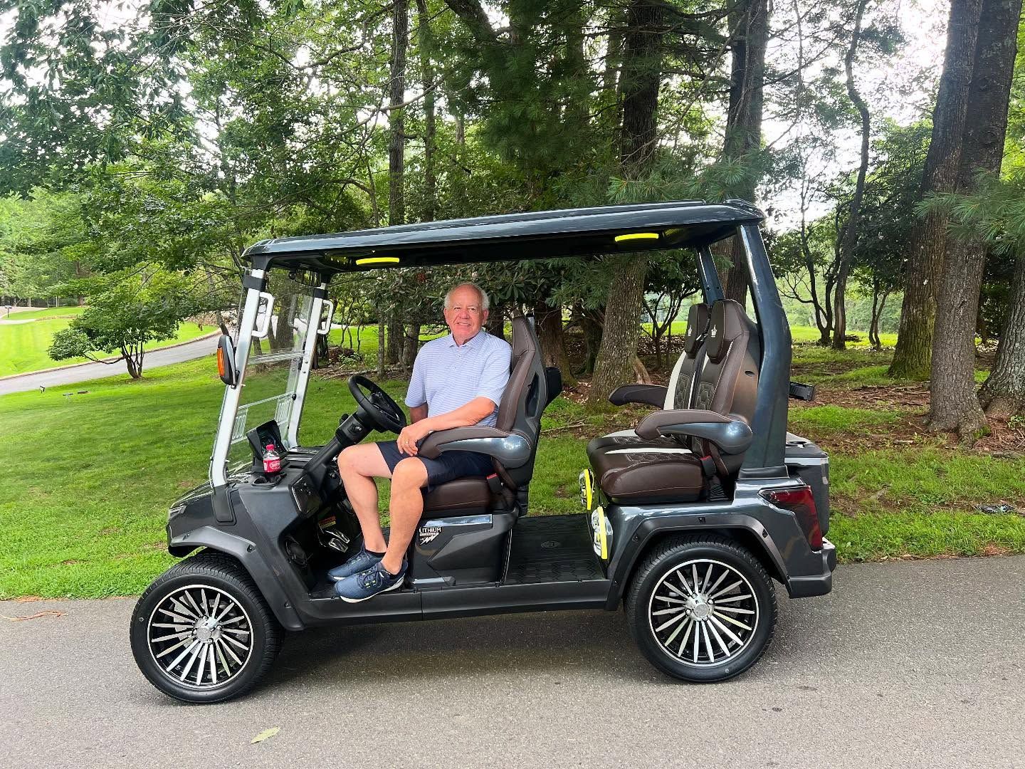 A man is sitting in a golf cart on a golf course.