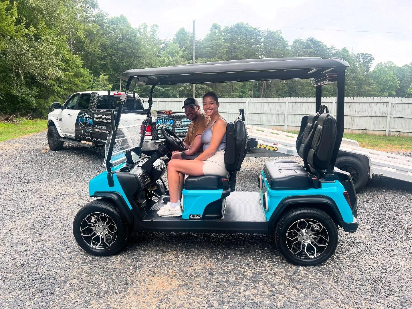A man and a woman are sitting in a blue golf cart.