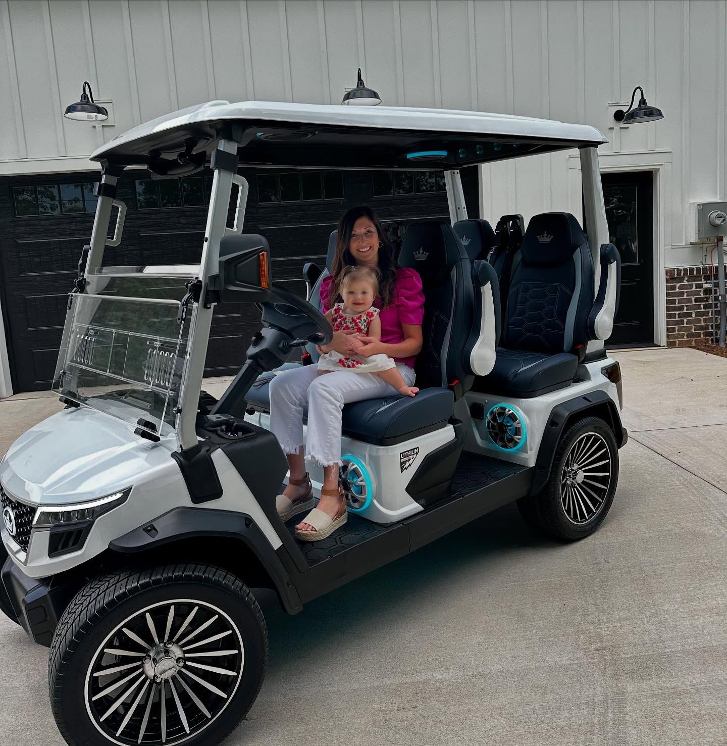 A woman and a baby are sitting in a golf cart.