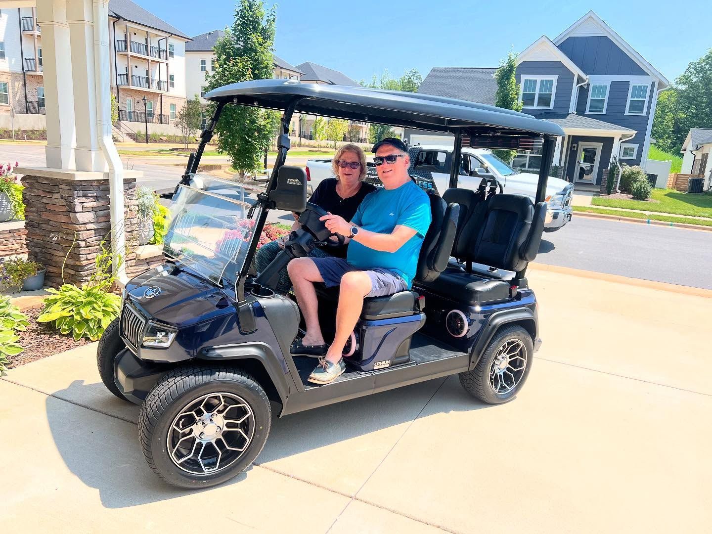 A man and a woman are sitting in a golf cart.