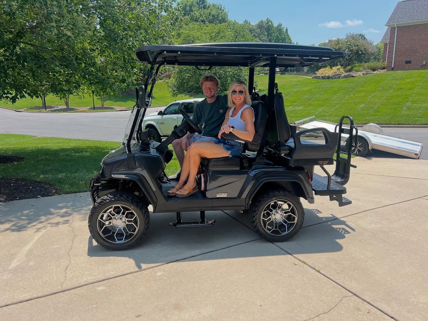 A man and a woman are sitting in a golf cart.