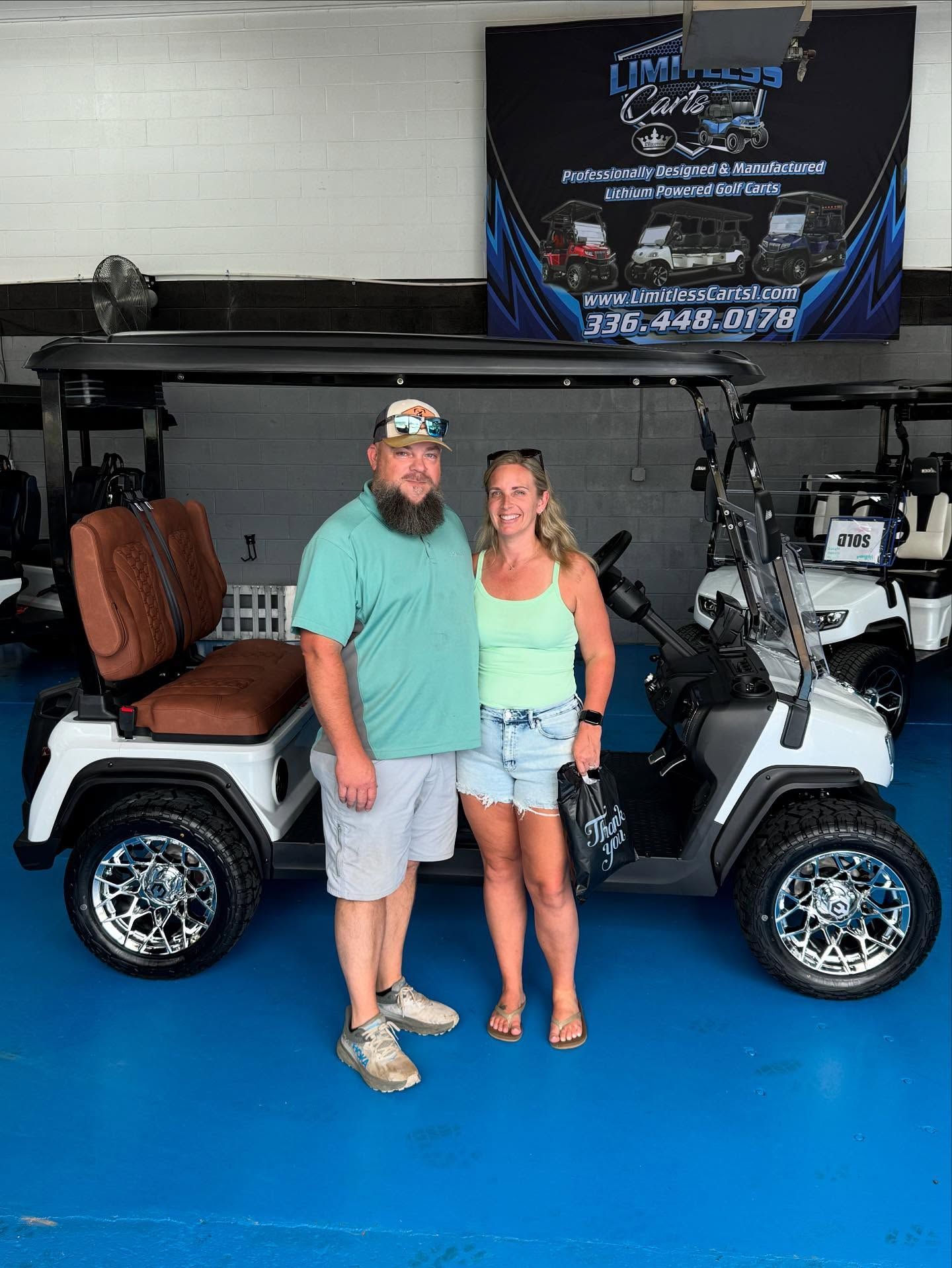 A man and a woman are standing in front of a golf cart.