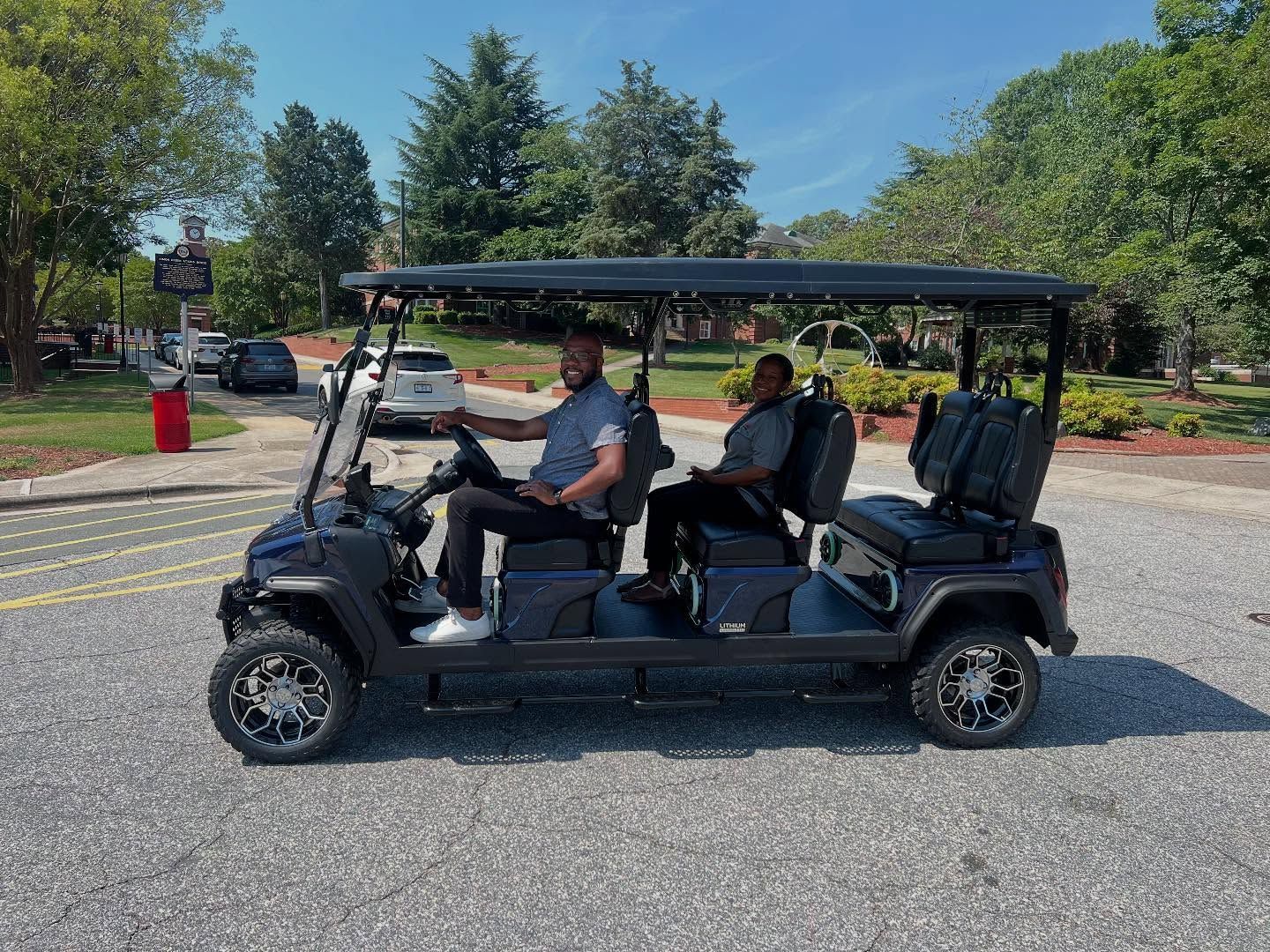 Two men are riding in a golf cart on a street.