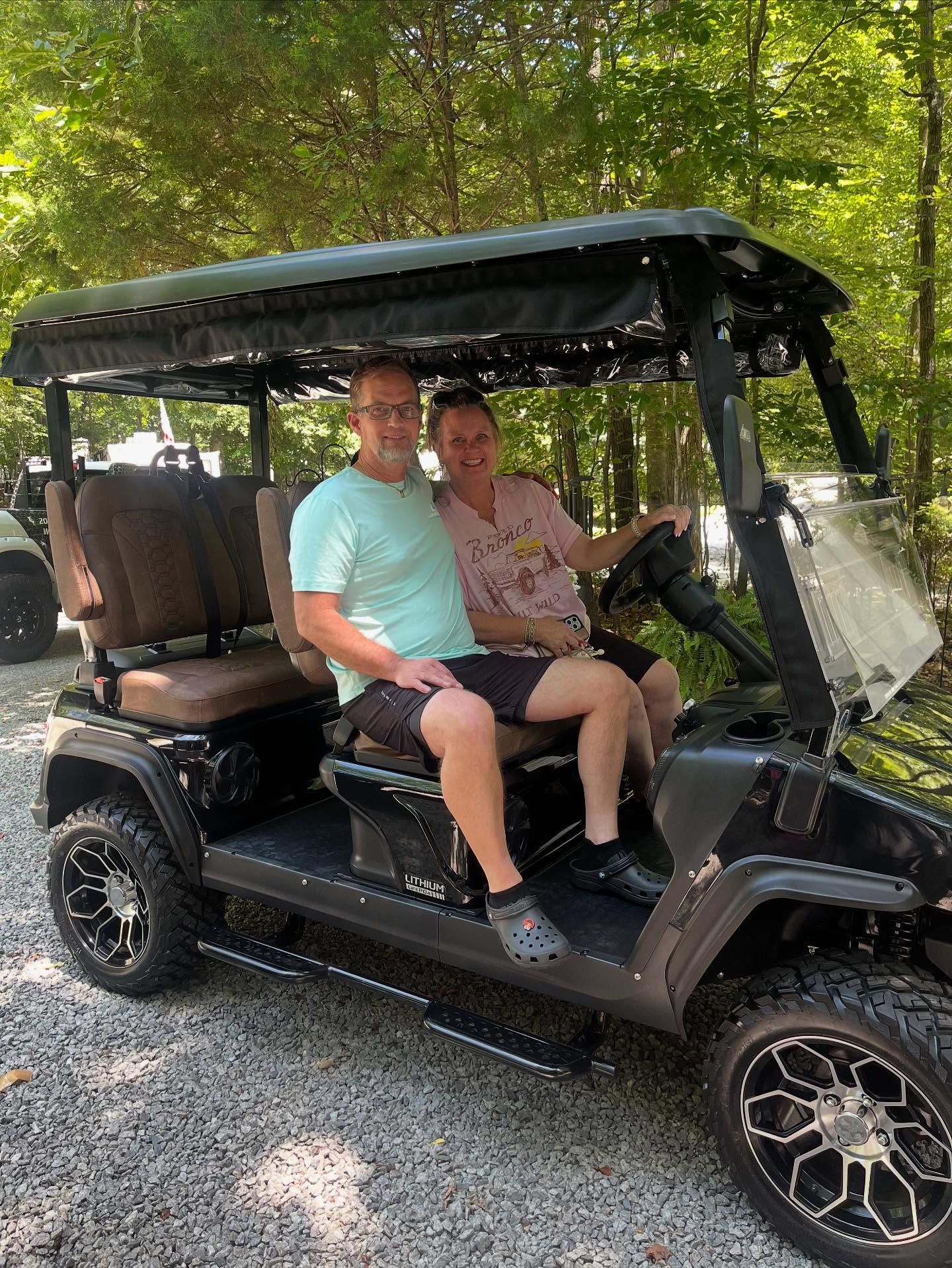 A man and a woman are sitting in a golf cart.