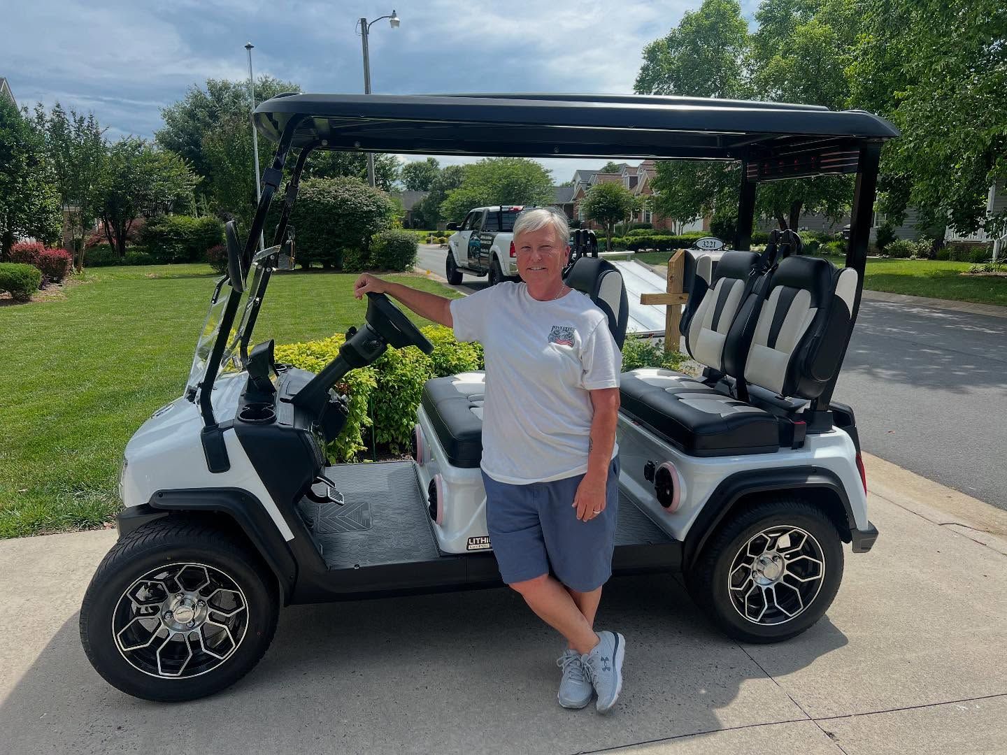 A man is standing next to a white golf cart.
