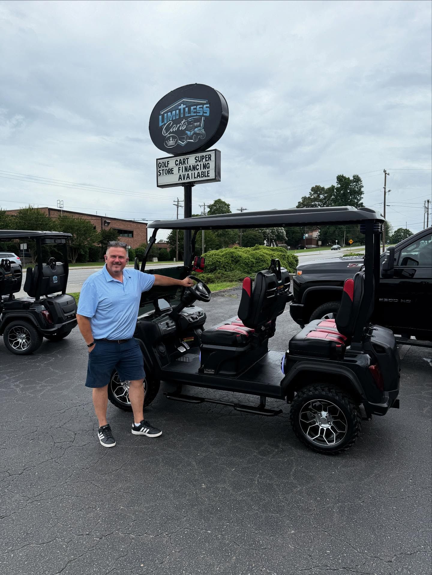 A man is standing next to a golf cart in a parking lot.