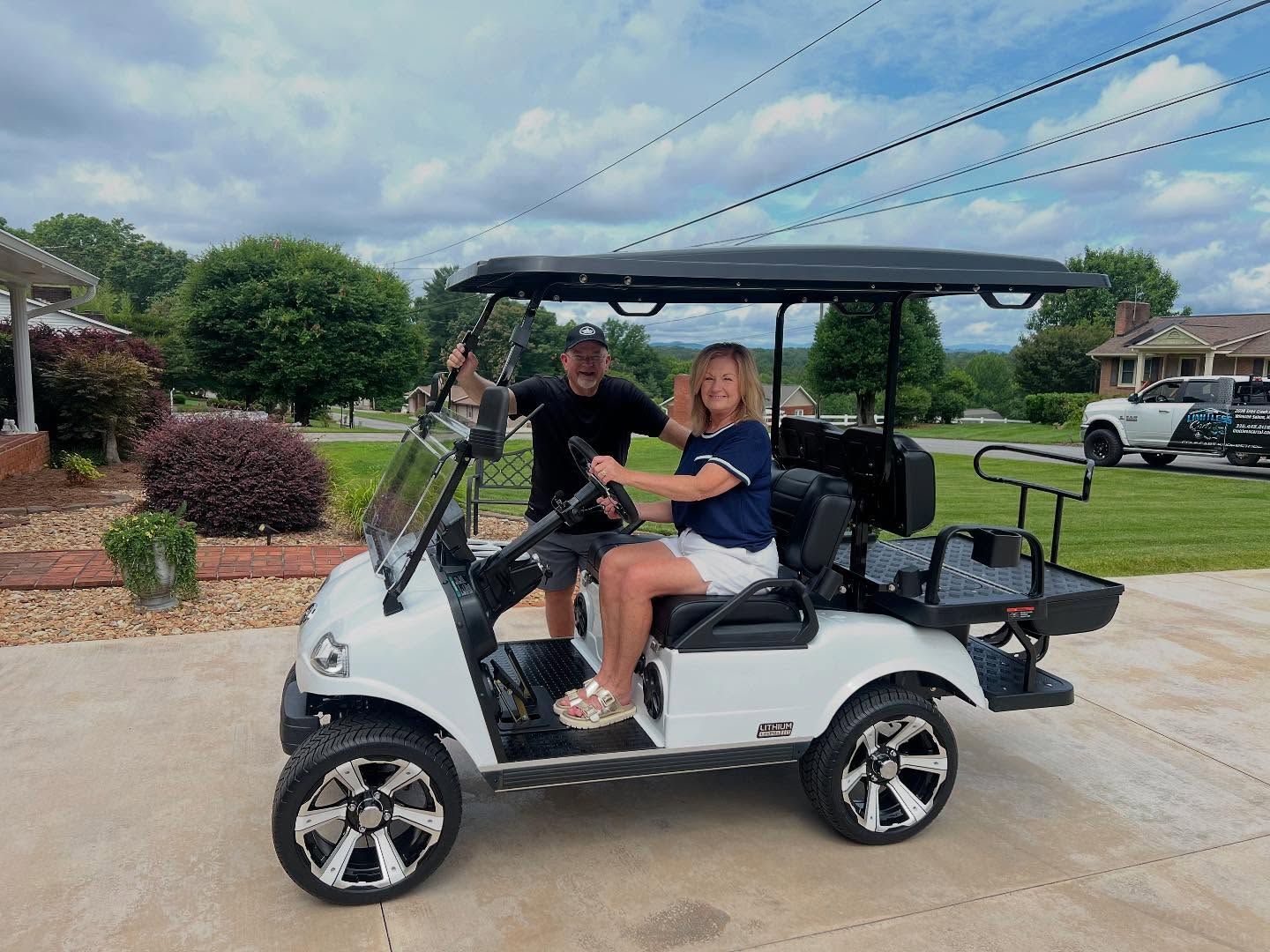 A man and a woman are sitting in a white golf cart.