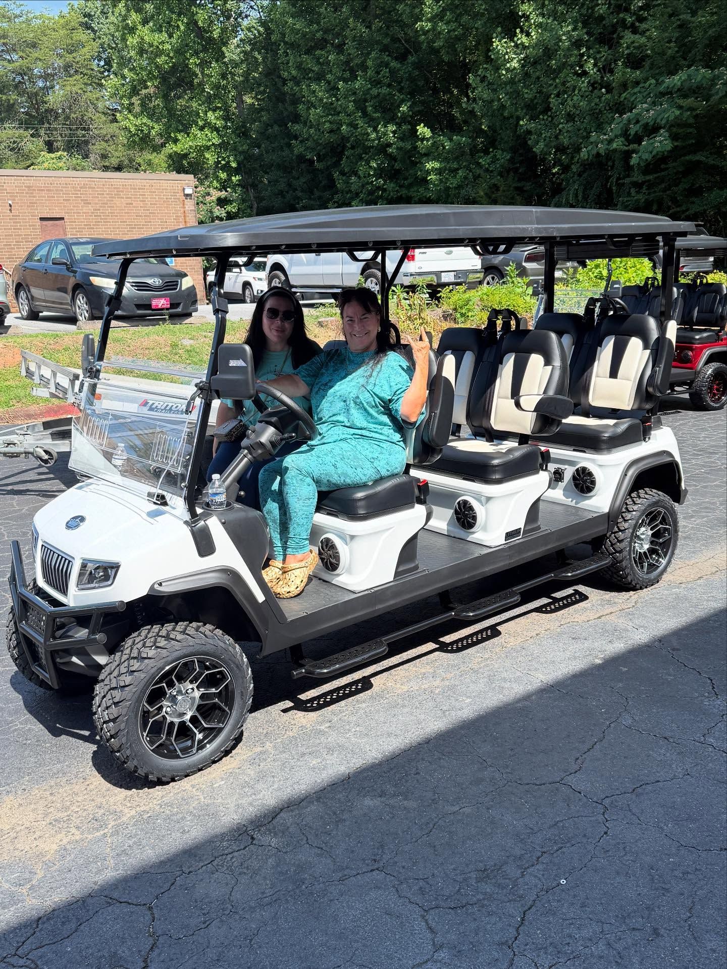 Two women are sitting in a golf cart.