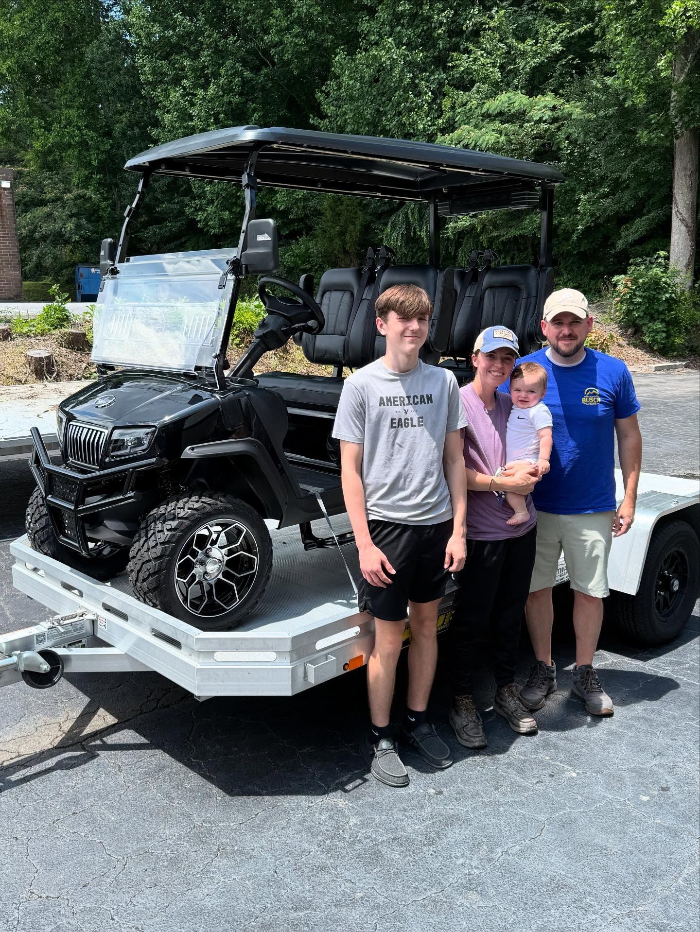 A family is standing next to a golf cart on a trailer.