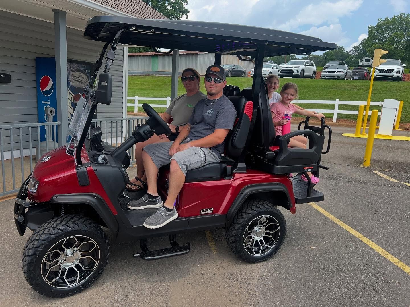 A group of people are sitting in a red golf cart.