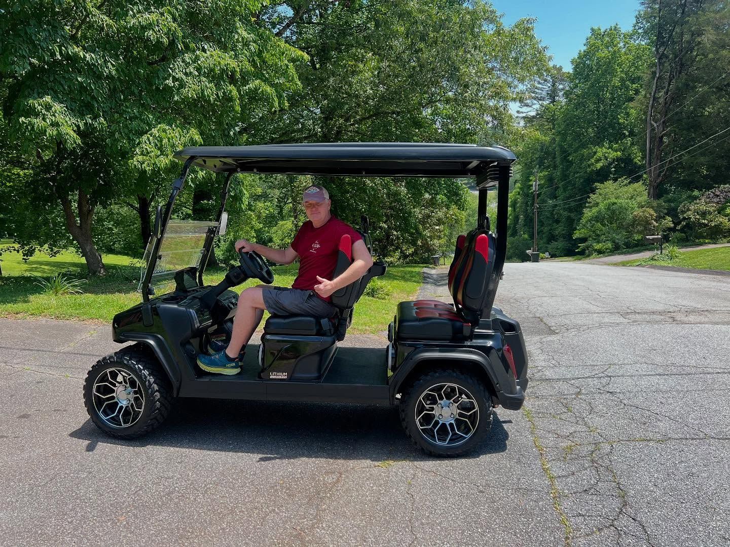 A man is sitting in a golf cart in a parking lot.
