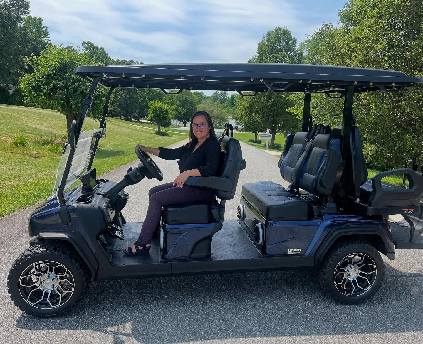 A woman is sitting in a golf cart on a road.