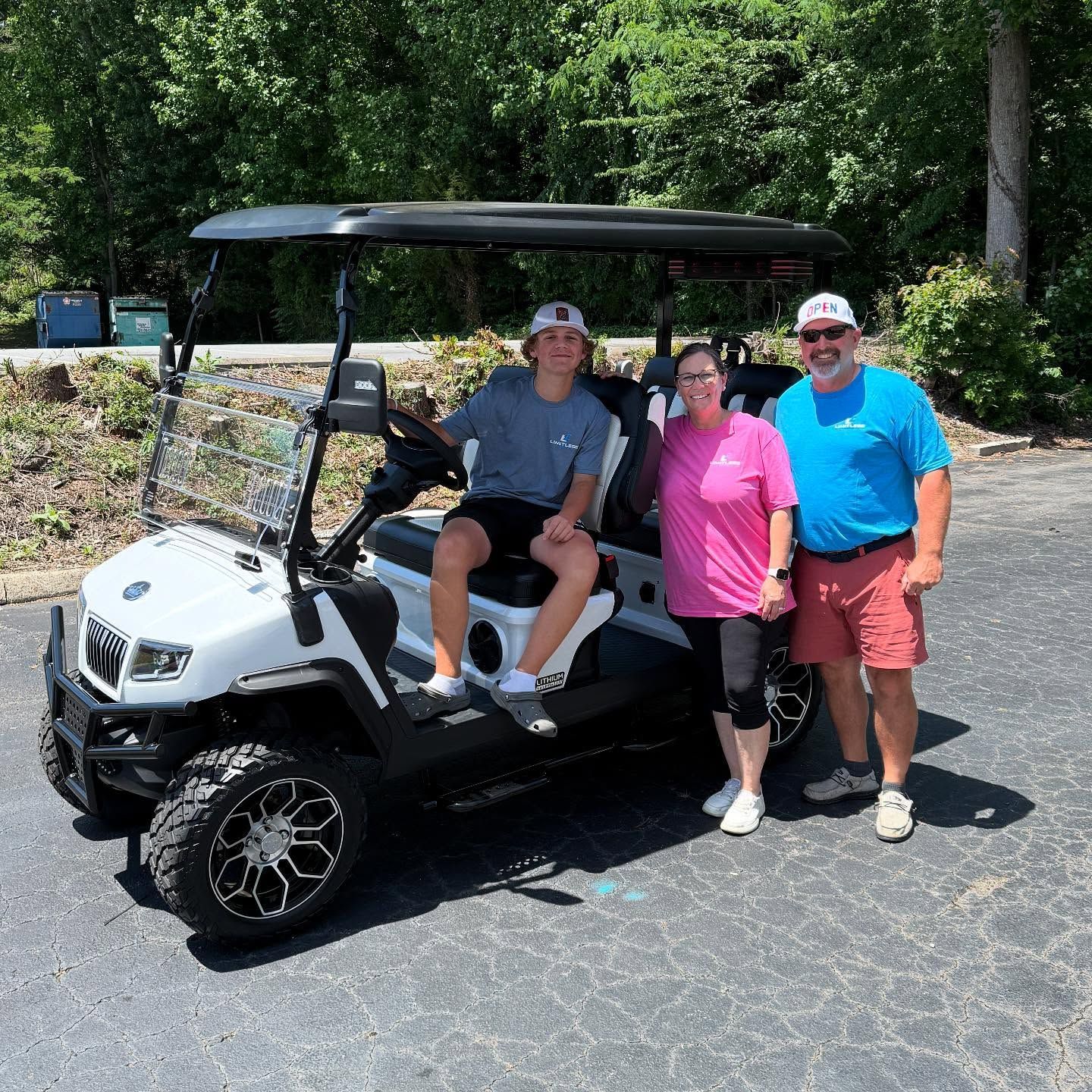 A man is sitting in a golf cart with two people standing next to it.